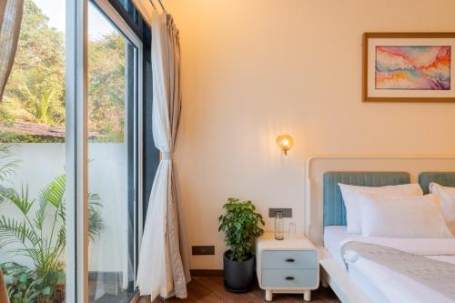 a bedroom with a bed and a large window at ELIVAAS Laguna Encanto 4 BHK Villa with Pvt Pool & Terrace in Anjuna
