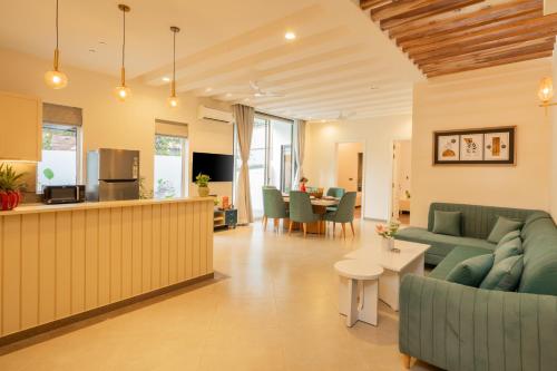 a living room with green couches and a kitchen at ELIVAAS Laguna Encanto 4 BHK Villa with Pvt Pool & Terrace in Anjuna