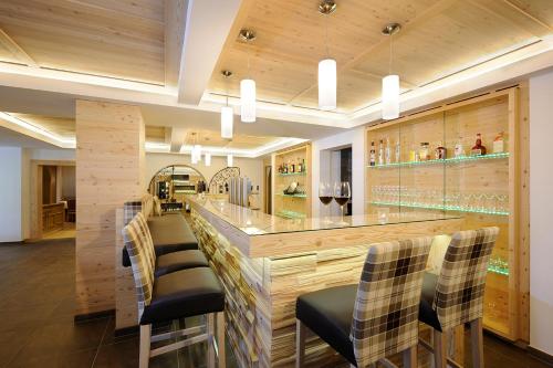 a bar with chairs and a counter with wine glasses at Hotel Marten - Ski-In & Ski-Out in Saalbach Hinterglemm