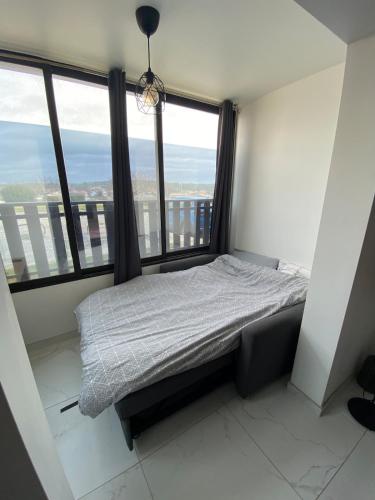 une chambre avec un lit dans une pièce avec des fenêtres dans l'établissement Studio Côte & Vague - Votre parenthèse océan à Lacanau, à Lacanau