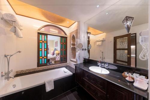 a bathroom with a tub and a sink and a mirror at SHEIK ISTANA HOTEL CHIANGMAl in Chiang Mai