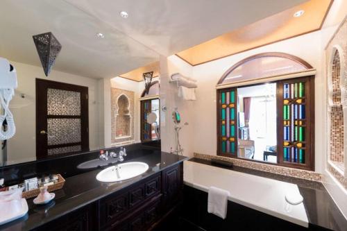 a bathroom with a sink and a large mirror at SHEIK ISTANA HOTEL CHIANGMAl in Chiang Mai