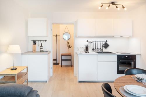 eine Küche und ein Wohnzimmer mit weißen Schränken und einem Tisch in der Unterkunft Ferienwohnung Sonnenglück mit großzügigem Südbalkon in Lenzkirch