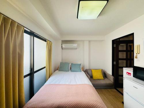 a small bedroom with a bed and a couch at Palasto Hostel in Tokyo