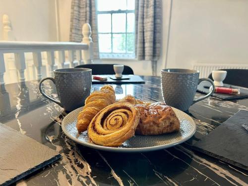 a plate of pastries on a table with two cups at Townside Hideaway in Guisborough