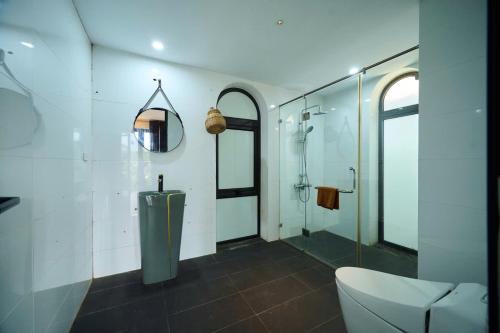 a bathroom with a shower and a toilet and a mirror at Mật Retreat in Ba Vì
