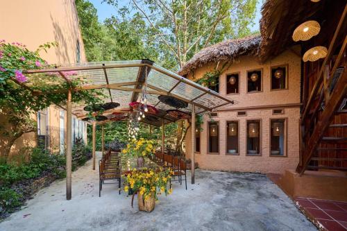 an outdoor patio with chairs and a thatch roof at Mật Retreat in Ba Vì