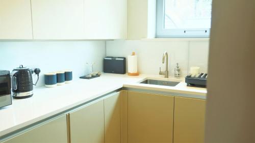 a kitchen with yellow cabinets and a sink and a microwave at Spacious & Elegant Apartments in Southbank near London Eye in London