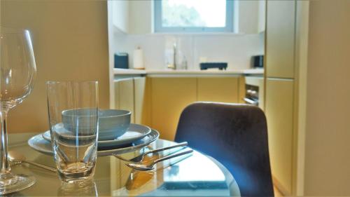 a glass table with a chair and a plate and glasses at Spacious & Elegant Apartments in Southbank near London Eye in London