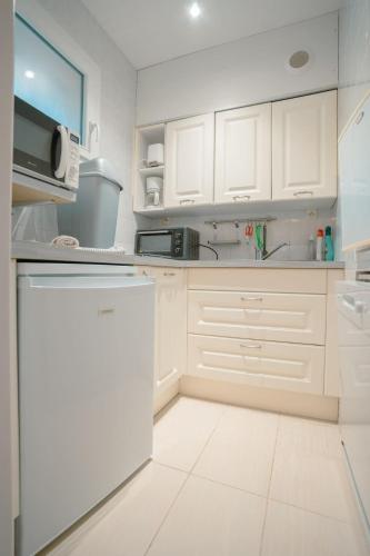 - une cuisine blanche avec des placards blancs et un lave-vaisselle dans l'établissement Studio Coté Jardin, à Gréoux-les-Bains