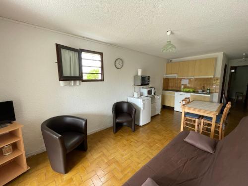 un salon avec un canapé et des chaises et une cuisine dans l'établissement Réf 434 Seignosse océan, appartement classé 2 étoiles, accès direct à l'océan et place de parking privée, 4 personnes, à Seignosse