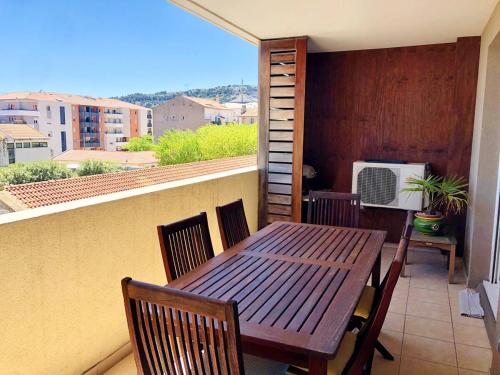 d'une table et de chaises en bois sur un balcon avec une fenêtre. dans l'établissement Grand Bleu T3 sur quai plaisancier, Garage, Clim, à Sète