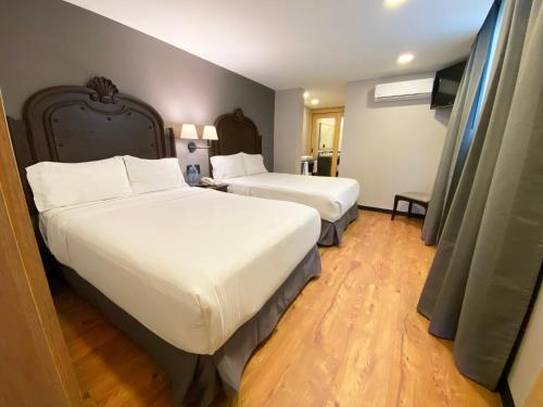 a hotel room with two beds with white sheets at Canada Central & Rooftop in Mexico City