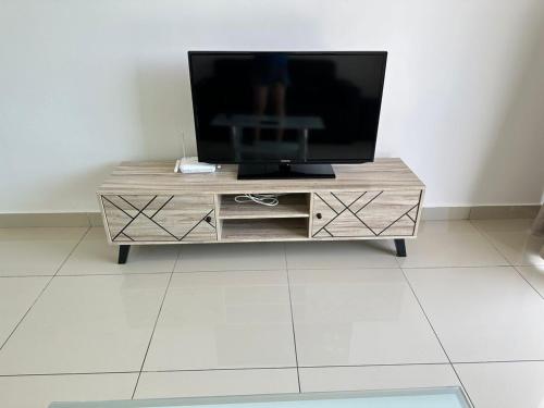 TV en la parte superior de un centro de entretenimiento de madera en HappySty, en Bayan Lepas