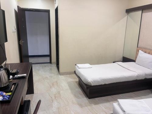a bedroom with a bed and a desk and a door at HOTEL SHIVGANGA COMFORT ZONE, Raipur in Raipur
