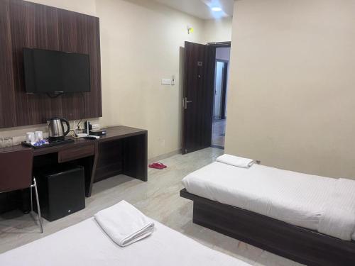 a hotel room with a bed and a desk and a television at HOTEL SHIVGANGA COMFORT ZONE, Raipur in Raipur