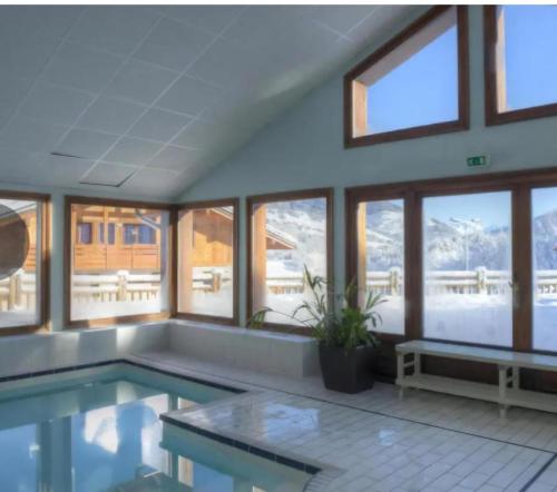 une grande piscine intérieure avec une table et des fenêtres dans l'établissement Chalet des Evettes, à Flumet