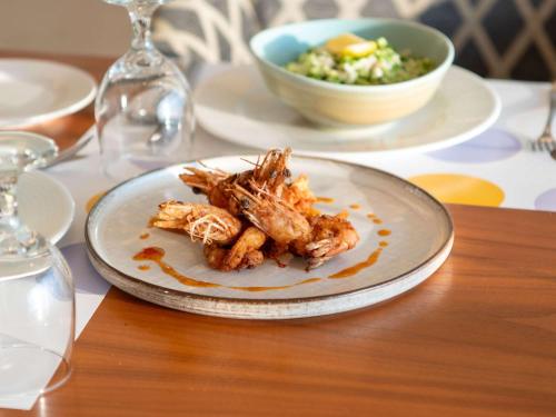 a plate of food on a table with a bowl of salad at Novotel Jazan in Jazan