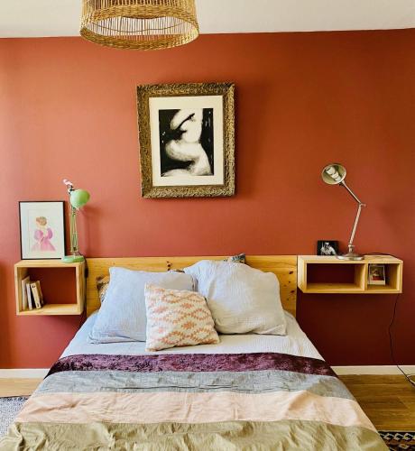 - une chambre avec un mur orange et un lit dans l'établissement Maison de ville entre Darwin et Jardin botanique, à Bordeaux