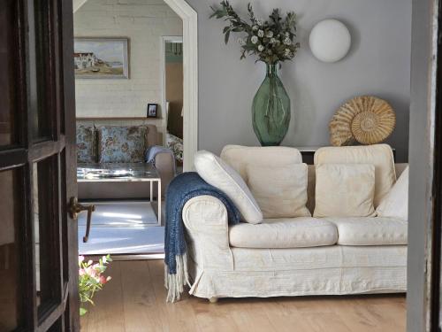 a living room with a white couch and a vase of flowers at Queen Anne Cottage in Guildford