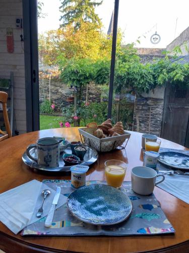 une table avec des assiettes de nourriture et une corbeille de pain dans l'établissement Chambre d'hôtes sur le chemin de la Loire à vélo, à Les Ponts-de-Cé