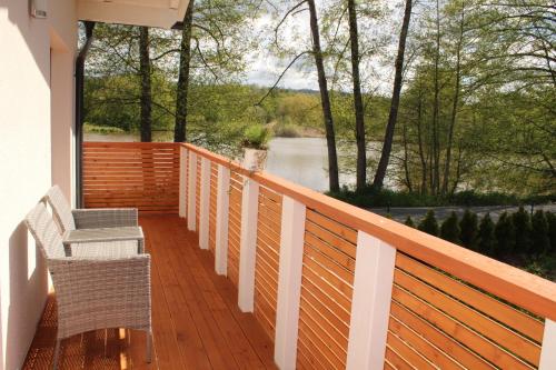 a wooden deck with chairs and a view of a river at Ferienhaus am Mühlteich in Lindenberg