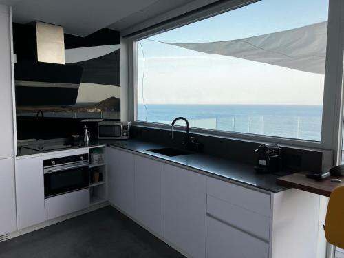 a kitchen with a sink and a large window at Los Genoveses Penthouse in San José