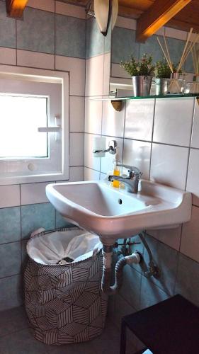 a sink in a bathroom with a basket under it at Cosy Loft Apartment, Argyrades in Argyrádes