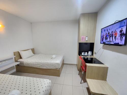 a small room with two beds and a flat screen tv at Kozi Hotel - Danga Bay in Johor Bahru