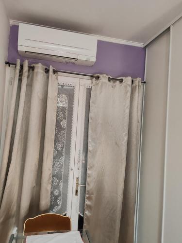 Cette chambre dispose d'une fenêtre avec des rideaux et du chauffage. dans l'établissement GITE Chez Marilou, à Aulnay-sous-Bois