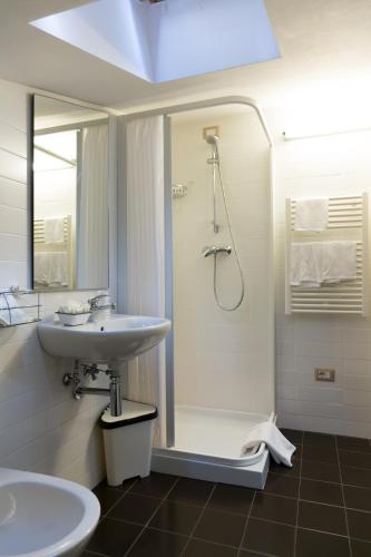 a white bathroom with a shower and a sink at Hotel Miramare in Pineto