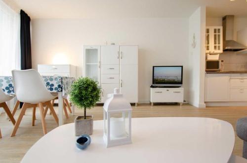 un soggiorno bianco con tavolo e TV di FeWo Heimathafen a Kellenhusen