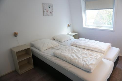 1 cama blanca con 2 almohadas y ventana en Kustverhuur, Park Schoneveld, Zeester 68, en Breskens