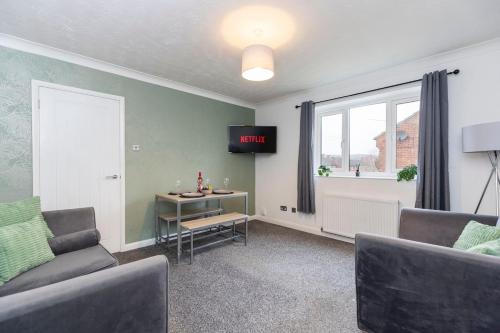 a living room with a couch and a table and a clock at Quiet corner haven in Guisborough