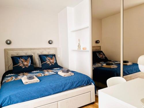 a bedroom with a bed with blue sheets and a mirror at Charmant cocon au cœur de Montmartre in Paris