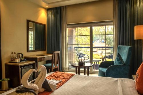 ein Hotelzimmer mit Bett und Balkon in der Unterkunft Basilica Resort - Where Luxury Redefines in Mahabaleshwar