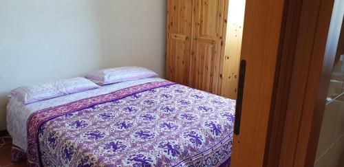a bedroom with a bed with a purple and white quilt at Vacanze a Rovere in Rovere