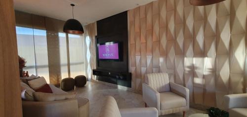 a living room with two chairs and a television at Nordeste Palace Hotel - Glória-SE in Nossa Senhora da Glória