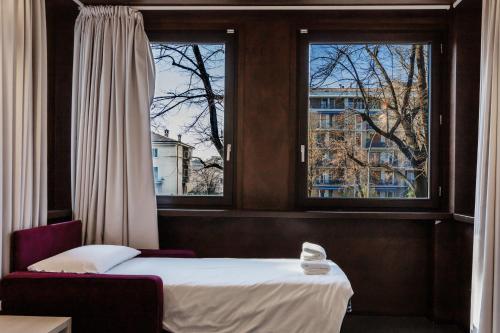 a bedroom with a bed and two windows at StraVagante Hostel & Rooms in Verona