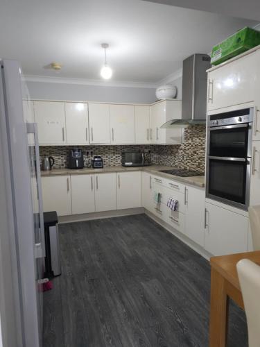 a kitchen with white cabinets and black appliances at Lux Home in Dagenham