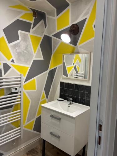 La salle de bains est pourvue d'un lavabo blanc et d'un mur jaune et gris. dans l'établissement Studio avec cour, à Briare