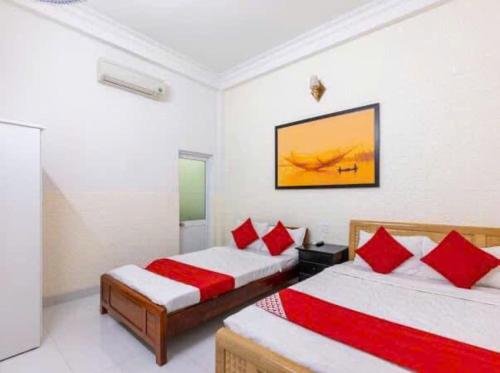 a bedroom with two beds with red pillows at Bong House Homestay in Hoi An