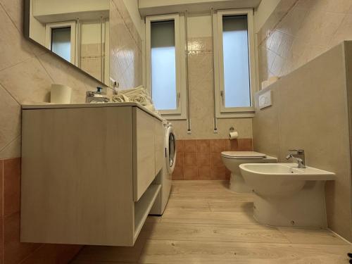 a bathroom with a sink and a toilet and windows at Il Villino Lido Spina in Lido di Spina