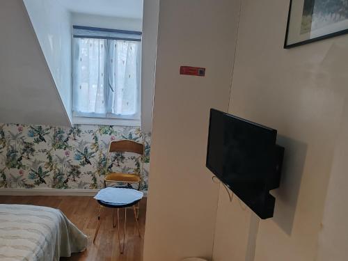 Un dormitorio con un televisor de pantalla plana en una pared. en GITE Chez Marilou, en Aulnay-sous-Bois