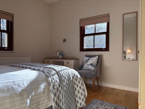 a bedroom with a bed and a chair and windows at Cottage 474 - Kylemore in Kylemore