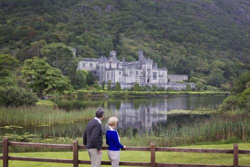 a man and a woman standing in front of a castle at Cottage 474 - Kylemore in Kylemore