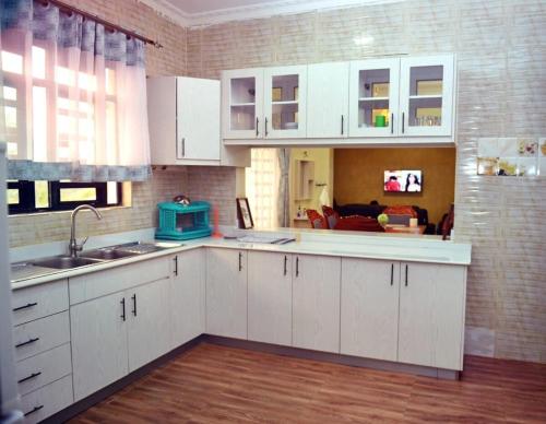 a kitchen with white cabinets and a living room at Plush Serene home next to Thika Greens Golf Estate in Thika