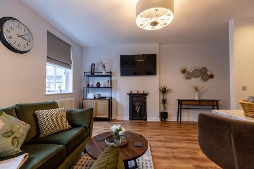 a living room with a couch and a clock on the wall at The York House Luxury Apartment located in Llandudno in Llandudno