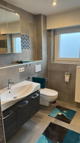 a bathroom with a sink and a toilet and a window at Moderne Wohnung in Achern, Schwarzwald in Achern