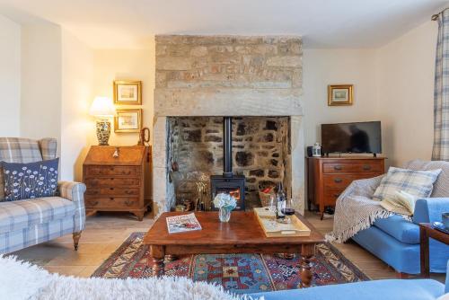 a living room with a stone fireplace and a table at Puddler's Cottage in Bedlington